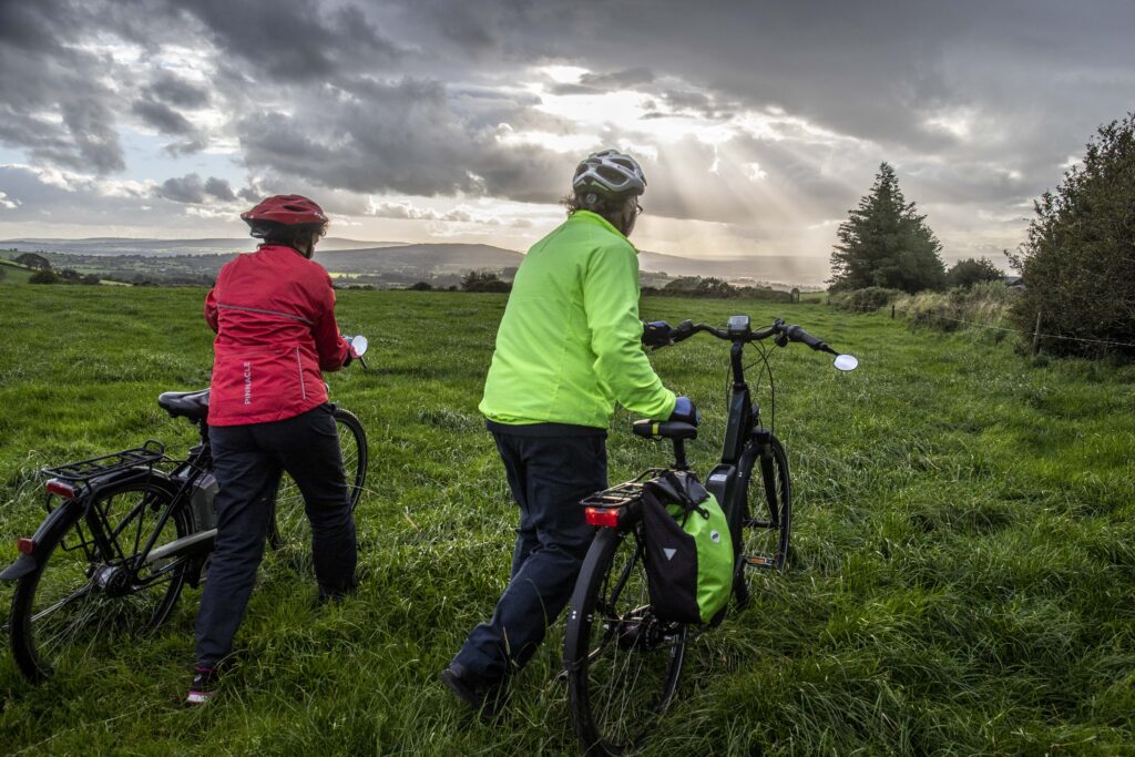 Paddy and Anna Lane of Mallow, Co. Cork walking through fields with their electric bicycles.