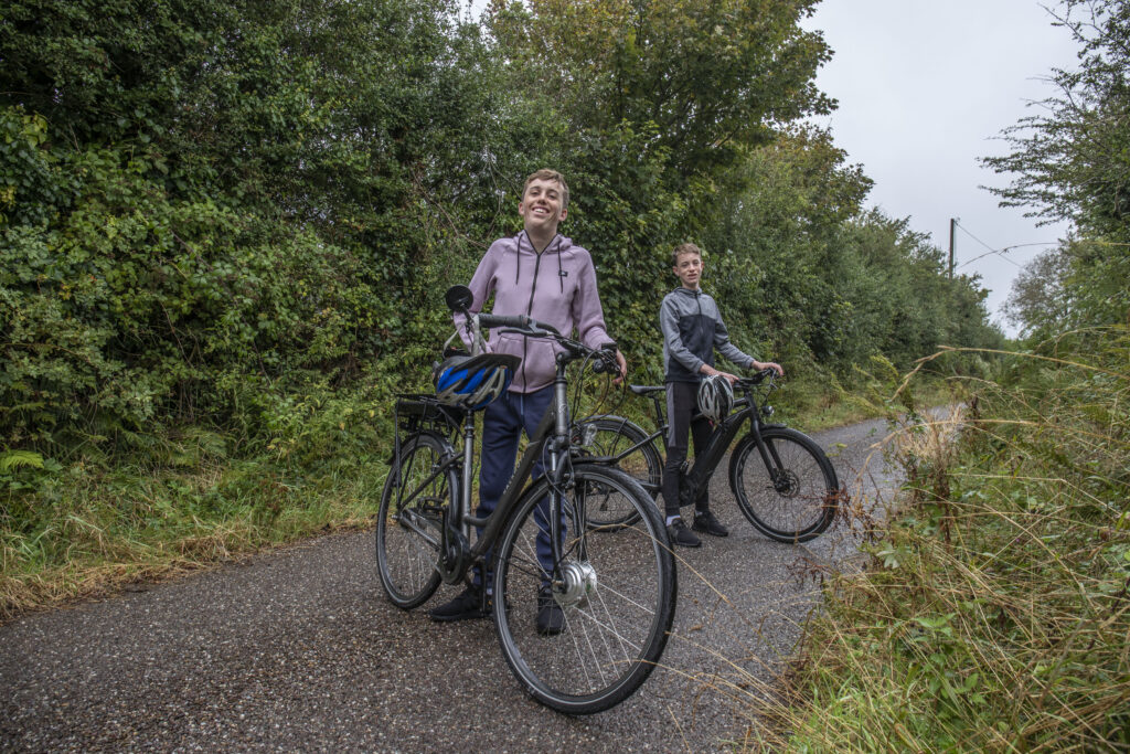 Conor O’Callaghan and his younger brother, Cormac, on a country road with their electric bicycles.