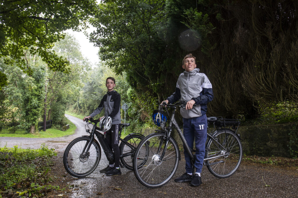 Conor O’Callaghan and his younger brother, Cormac, of Kinsale, County Cork on a country road with their electric bicycles.