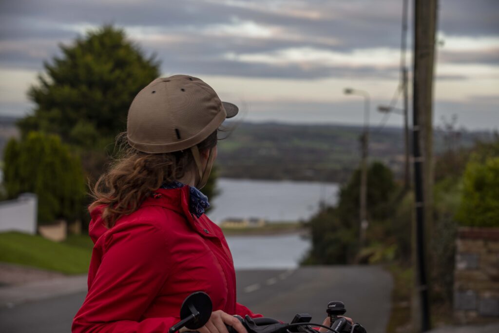 Teresa Watkins of Youghal, Co. Cork with her electric bicycle looking down a road towards water.